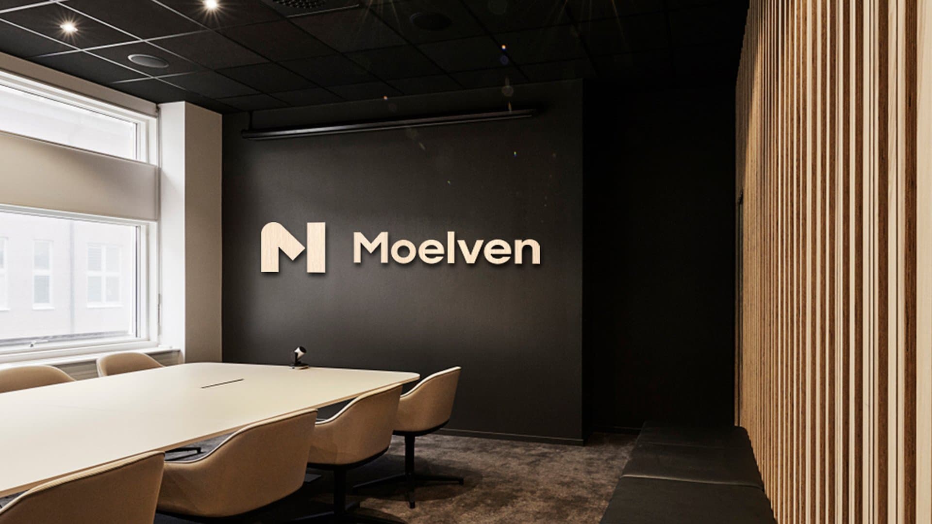 Moelven sin logo på en vegg i et møterom
