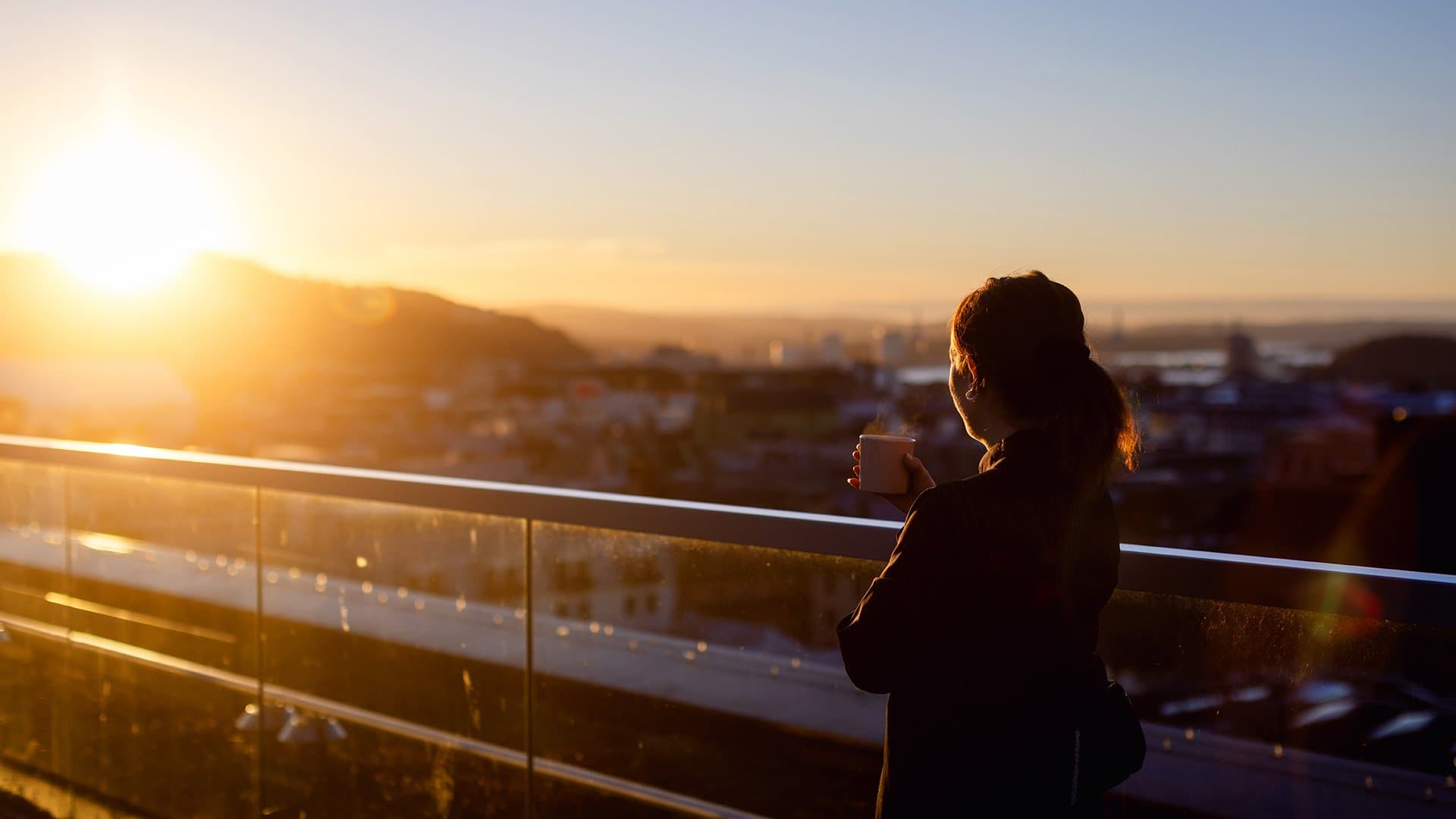 Kvinne med en kaffekopp i solen