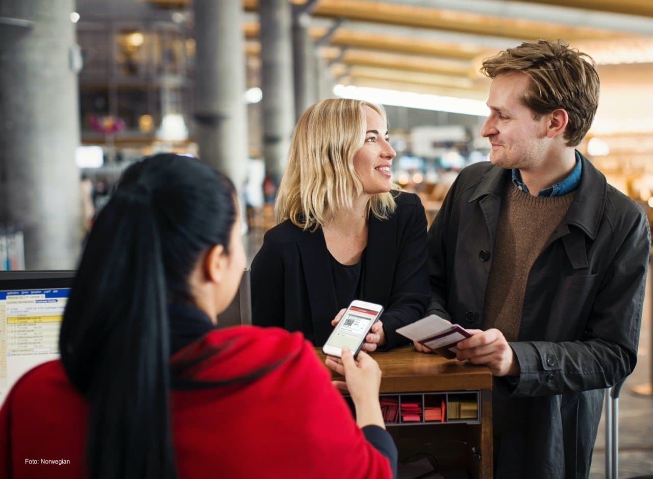 Folk på en flyplass som sjekker inn